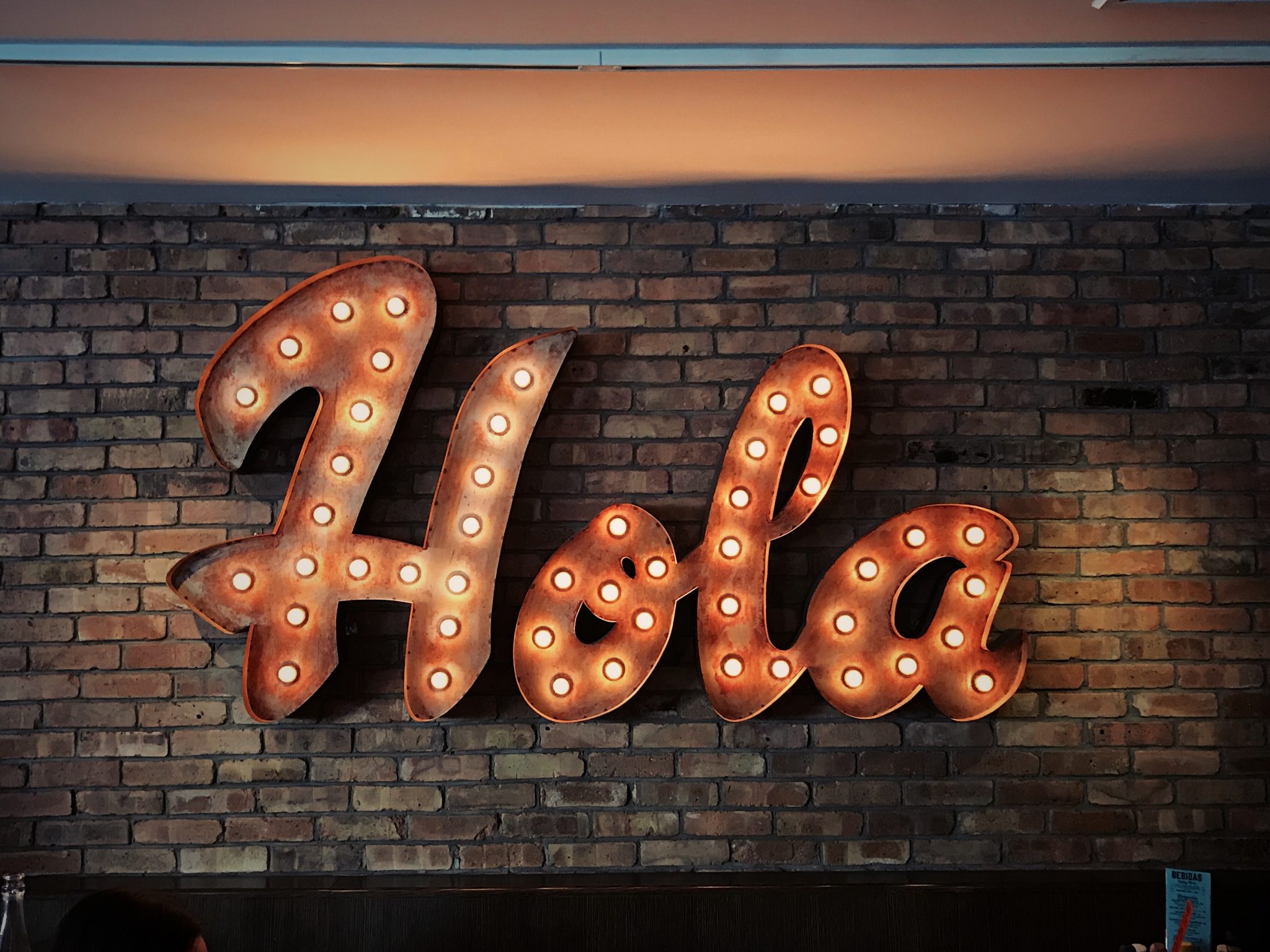 LED Hola sign on brick wall